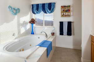 Full bath featuring a jetted tub and vanity