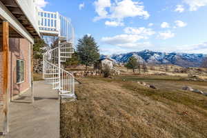 View of green lawn with stairway, a patio, and a mountain view