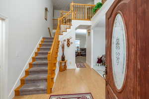 Foyer entrance with wood finished floors, a high ceiling, stairs, and arched walkways