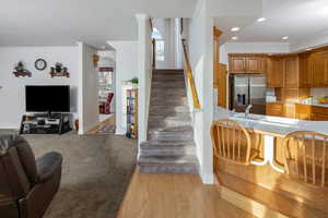 Living room with ornamental molding, stairs, light wood-type flooring, recessed lighting, and light colored carpet