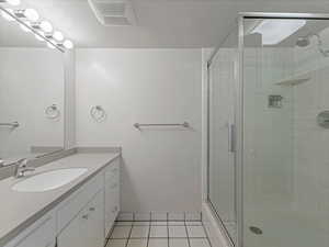 Bathroom featuring a stall shower, vanity, and tile patterned flooring