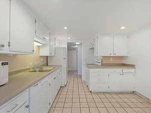 Kitchen with white appliances, white cabinetry, recessed lighting, light countertops, and light tile patterned floors