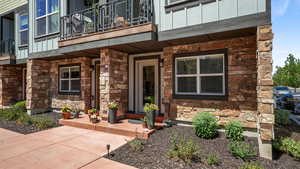 Entrance to property featuring a balcony, stone siding, and board and batten siding