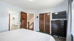 Bedroom with dark wood finished floors, a closet, and ensuite bath