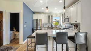 Kitchen with a peninsula, tasteful backsplash, stainless steel appliances, vaulted ceiling, and glass insert cabinets