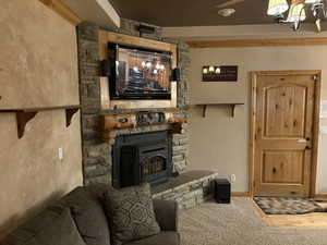 Living area featuring wood finished floors, a chandelier, and a stone fireplace