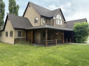 Rear view of house featuring stone siding, stucco siding, and a yard
