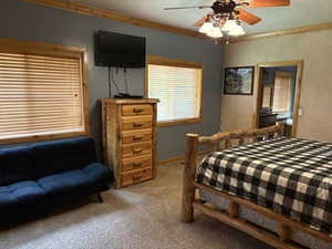Bedroom featuring ornamental molding, light carpet, and ceiling fan