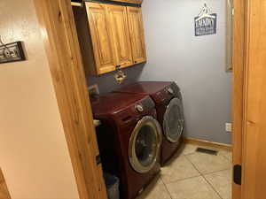 Laundry area with cabinet space, washing machine and dryer, and light tile patterned floors