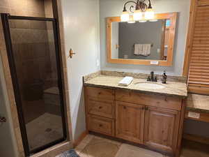 Full bathroom featuring tile patterned flooring, a stall shower, and vanity
