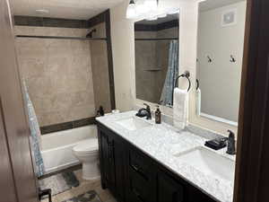 Bathroom featuring a textured ceiling, double vanity, shower / bath combo, and tile patterned flooring