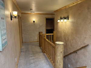 Corridor with an upstairs landing, ornamental molding, carpet floors, and a textured ceiling