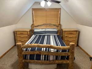 Bedroom featuring a textured ceiling, carpet flooring, a ceiling fan, and lofted ceiling