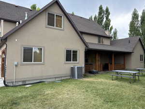 Back of property with stucco siding, a yard, and a shingled roof