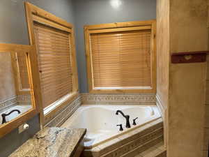 Full bathroom featuring a tub with jets and vanity