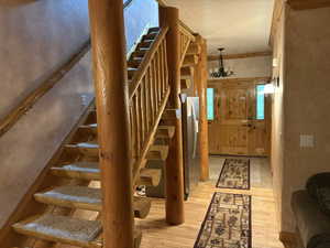 Stairs featuring wood-type flooring and a chandelier