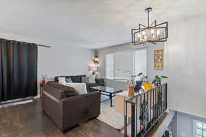 Living area with a chandelier, a textured ceiling, and dark wood finished floors