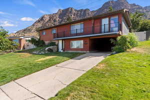 View of front of house with a mountain view, driveway, and a front yard