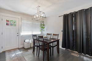 Dining room featuring a textured ceiling, a chandelier, and dark wood finished floors