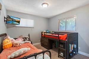 Carpeted bedroom with baseboards and a textured ceiling