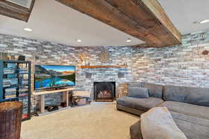 Carpeted living area with brick wall, recessed lighting, and a brick fireplace