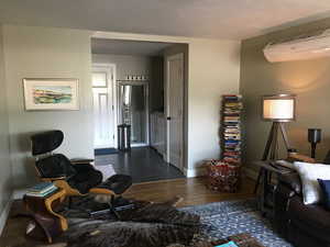 Living room with wood finished floors and a wall mounted air conditioner