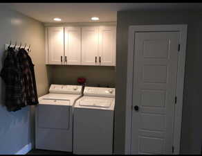 Laundry area with independent washer and dryer, cabinet space, and recessed lighting