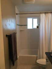 Bathroom featuring vanity, shower / tub combo with curtain, and tile patterned floors
