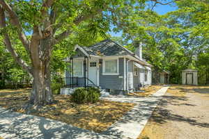 Bungalow-style home with a shed, a chimney, and driveway
