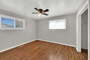 Unfurnished bedroom with wood finished floors, a closet, and a ceiling fan