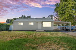Single story home featuring a carport, driveway, and roof with shingles