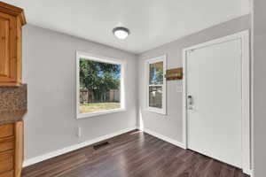 Unfurnished dining area featuring dark wood-style flooring and baseboards
