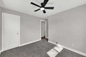 Carpeted spare room featuring baseboards and a ceiling fan