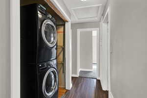 Laundry area featuring estacked washer and dryer, wood finished floors, and attic access