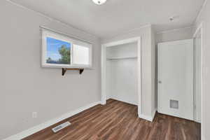 Unfurnished bedroom with dark wood-style floors and a closet
