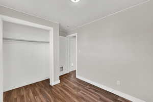 Unfurnished bedroom featuring dark wood finished floors and a closet