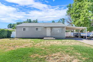 View of front of house featuring an attached carport, concrete driveway, and a shingled roof