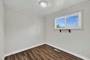 Spare room featuring dark wood-type flooring and a textured ceiling