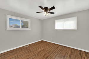 Empty room with wood finished floors, plenty of natural light, and ceiling fan