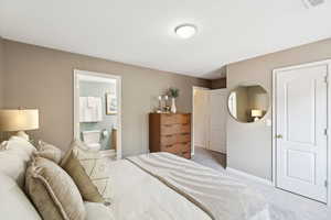 Bedroom featuring light carpet and ensuite bath