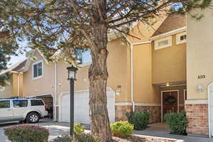 View of front of property featuring stucco siding, stone siding, an attached garage, and driveway