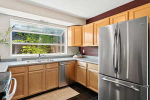 Kitchen with stainless steel appliances, light countertops, and dark tile patterned floors