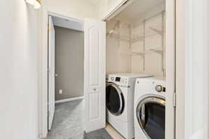 Laundry area featuring independent washer and dryer and light colored carpet