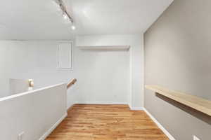 Hall featuring wood finished floors, rail lighting, and a textured ceiling