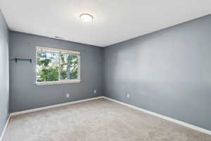 Carpeted empty room featuring a textured ceiling and baseboards