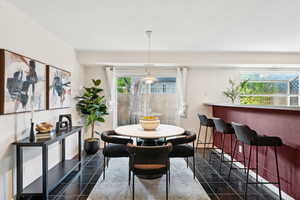 Dining area featuring plenty of natural light, dark tile patterned floors, and a bar