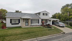 View of front of house featuring concrete driveway, an attached carport, a front yard, and roof with shingles