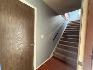 Staircase with baseboards and tile patterned flooring