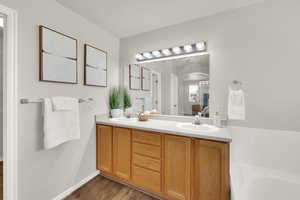 Full bath with double vanity, wood finished floors, and a tub