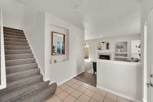 Stairs with carpet flooring, a tiled fireplace, and tile patterned floors